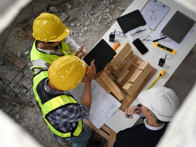 Civil engineering company reviewing site plans and development models during utility connection planning for a construction project