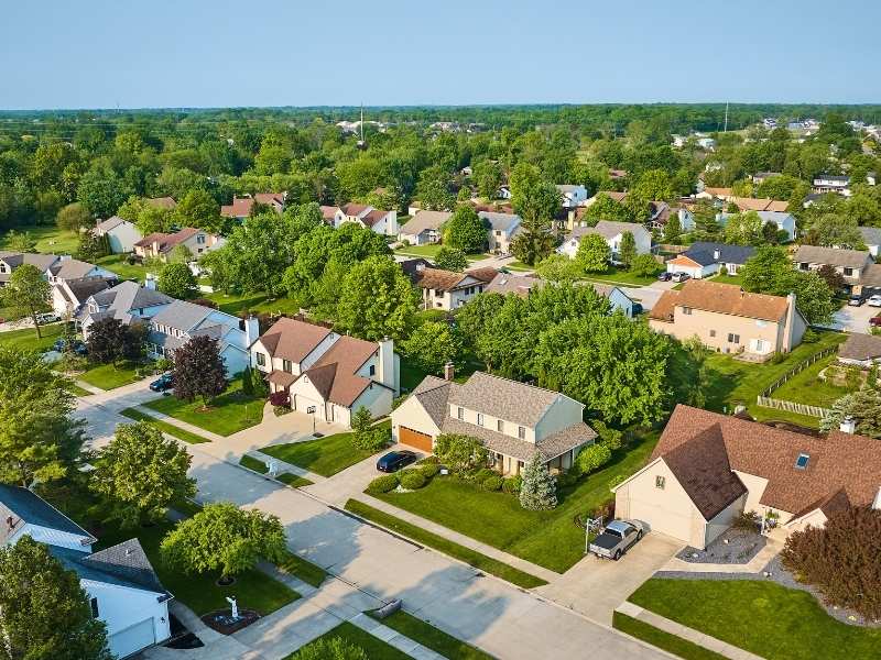 Aerial view of a residential subdivision with connected streets, homes, green spaces, and neighborhood layout supporting planned community growth.
