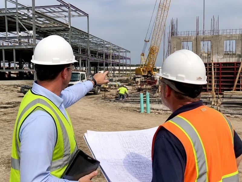 Construction manager reviewing project plans with contractors at an active commercial construction site in Atlanta, GA.